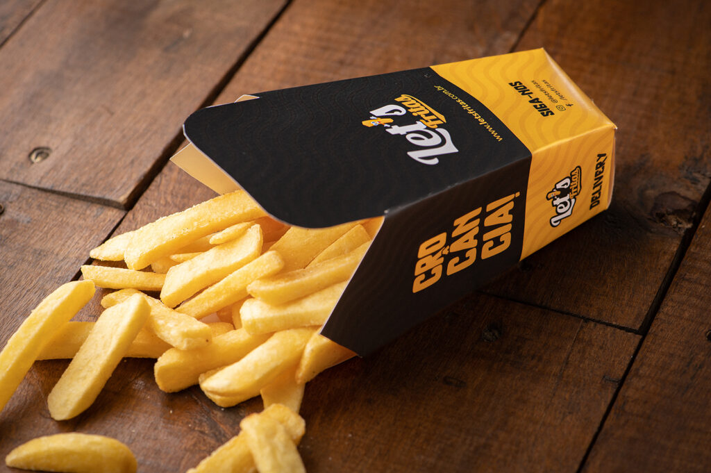 embalagem de batata frita de lado sobre uma mesa de madeira - Let's Fritas